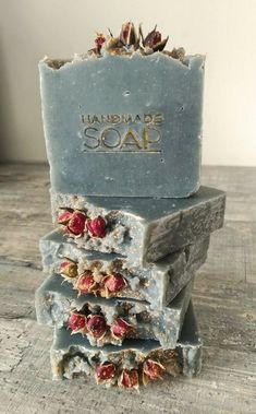 three soap bars stacked on top of each other with rose petals in the middle and one bar labeled handmade soap