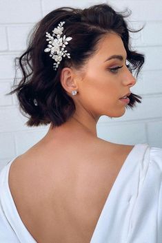 a woman wearing a white dress with a hair comb in her hair and earrings on her head