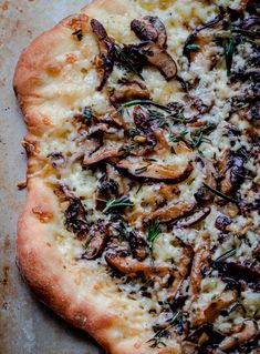 a close up of a pizza on a pan with mushrooms and herbs toppings in it