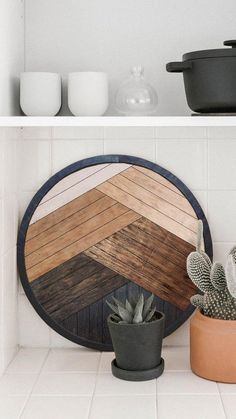 a potted cactus sitting next to a wooden cutting board on top of a shelf