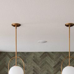 three lights hanging from the ceiling in a room with herringbone tiles on the wall