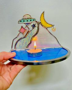 a person holding a plate with a lit candle in front of it and an image of a ship on top