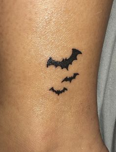 a small tattoo on the back of a woman's neck with bats flying above it