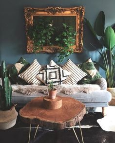 a living room filled with lots of plants next to a wooden table and mirror on the wall