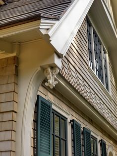 the corner of a house with green shutters and a white awning on it