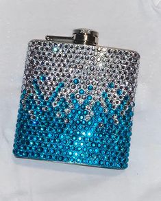 a blue and silver flask covered in crystal stones