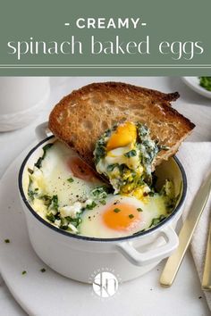 an egg and spinach breakfast in a white bowl with toast on the side next to it