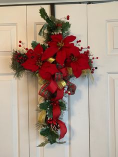 a cross decorated with poinsettis and pine cones hangs on the front door