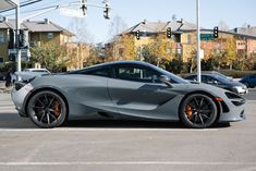 a gray sports car parked in the middle of a parking lot next to some houses