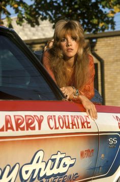 a woman sitting in the driver's seat of a car looking out the window