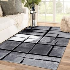 a living room with a white couch and black area rug on top of the floor