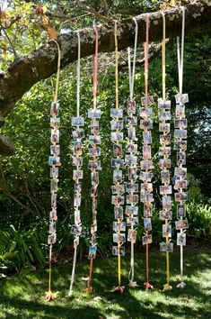 a wind chime with pictures hanging from it's sides in front of trees