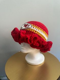 a red and white knitted hat with a football on the side sitting on a wooden table