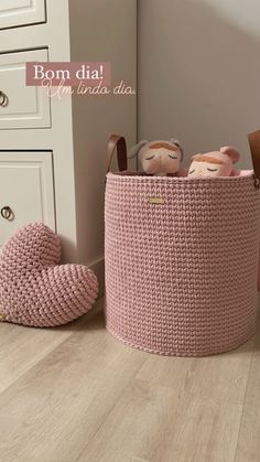 a pink basket with stuffed animals in it on the floor next to a white dresser