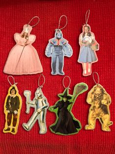 four christmas ornament shaped like children's characters on a red cloth background