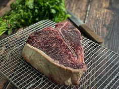 a piece of steak sitting on top of a metal rack next to some parsley