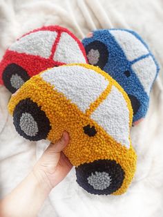 three crocheted cars sitting on top of a white blanket next to each other