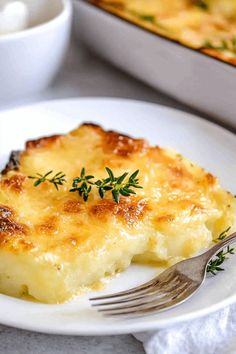 a white plate topped with mashed potatoes next to a casserole dish filled with cheese