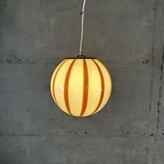 an orange and white striped light hanging from a ceiling fixture in a concrete wall room