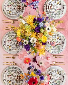 the table is set with colorful flowers and plates