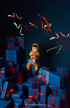 a baby sitting on top of blue boxes surrounded by streamers and confetti