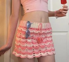 a woman in pink shirt and crochet skirt holding up an ice cream cone