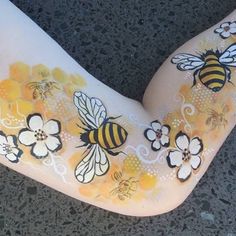 a woman's body painted with honeybees and flowers on the side of her leg