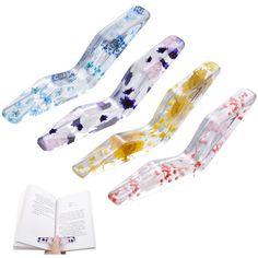 four different colored glass toothbrushes with an open book