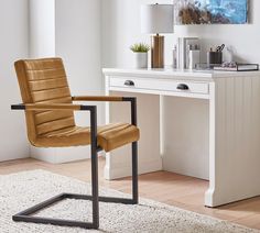 a brown leather chair sitting in front of a white desk with a painting on it