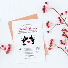 a wedding card with mickey and minnie mouses on it next to some red berries