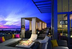 an image of a balcony with chairs and tables at night or day, overlooking the city