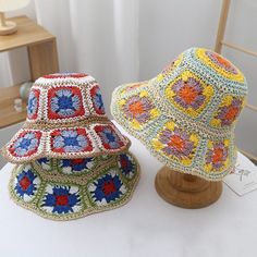 two crocheted hats sitting on top of a white table next to each other