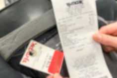 a person holding up a receipt in their hand