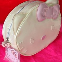 a hello kitty purse with a pink bow on the front and back side, sitting on a pink surface