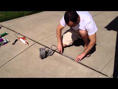 a man kneeling down on the ground working on an electrical wire with tools around him