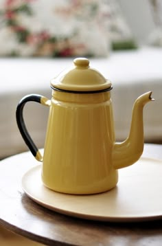 a yellow teapot sitting on top of a white plate