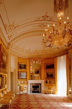 an ornate room with chandeliers and paintings on the walls, along with a fireplace