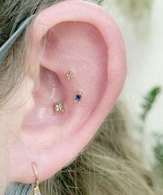 a close up of a person's ear with three different colored stones on it