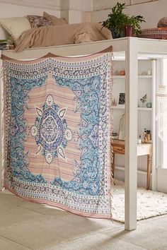 a large tapestry hanging from the side of a bed in a room with white walls