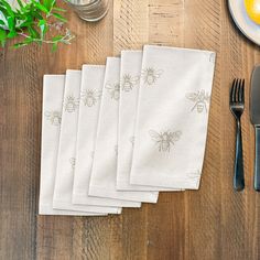 five bees printed napkins on top of a wooden table next to utensils