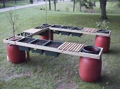 three planters sitting on top of wooden boards in the grass next to two red barrels