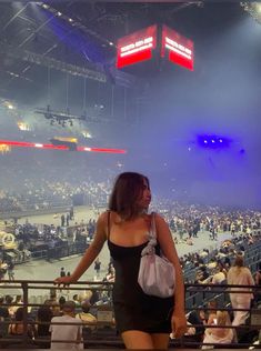 a woman standing in front of a crowd at a sporting event with her hand on her hip