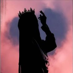 the silhouette of a man with a crown on his head is shown against a pink sky