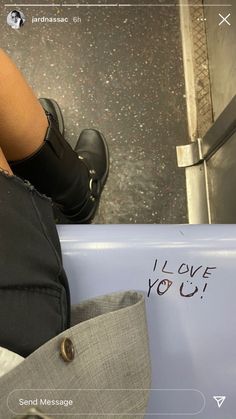 a person sitting on a bench with their legs crossed and writing i love you written on the seat