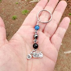 a hand holding a key chain with a motorcycle charm on it