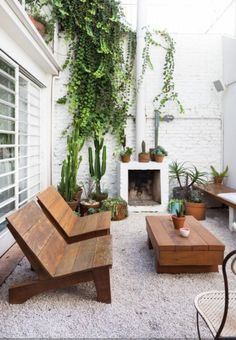 an outdoor living area with wooden furniture and potted plants on the wall, along with a fireplace