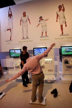 several people are standing in front of televisions playing wii