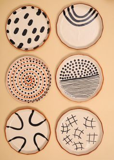 four plates with black and white designs are arranged on a beige surface, one is in the shape of a circle