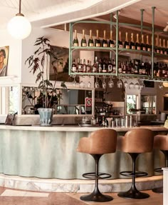 a bar with stools and bottles behind it