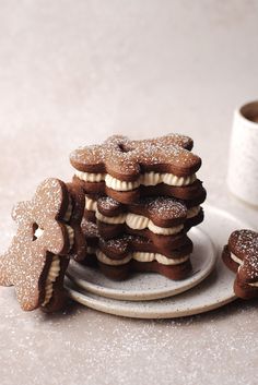 a stack of cookies sitting on top of a white plate next to a cup of coffee